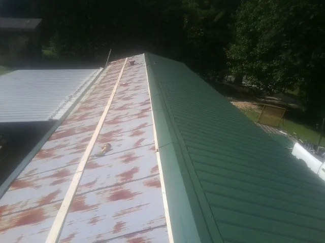 Old rusted panels beside newly installed green metal roofing — Wind Damage Roof Repair by Roofing Brothers in Lurgan