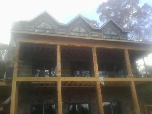 Dormers and porch framing on a large log home under construction — Roof Coating work by our crew in Lurgan