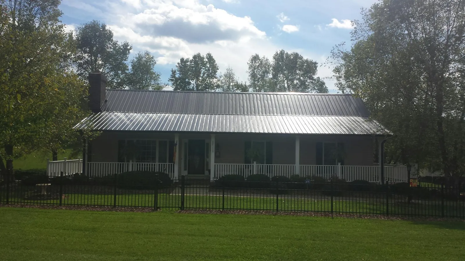 Gray metal roof on a brick ranch with a full width front porch — Gutter Guard Installation work by our crew in Lurgan
