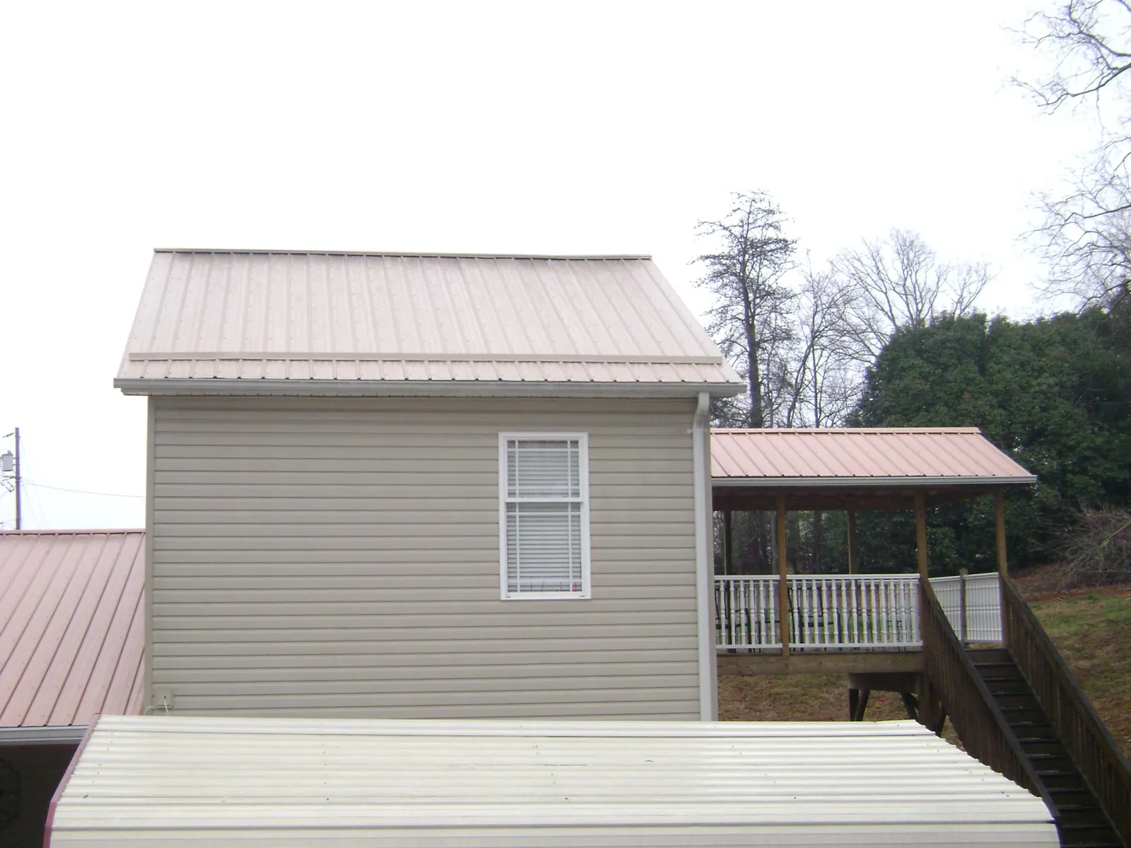 Tan metal roofs on a two story addition and attached porch, from a Roof Replacement job in Lurgan