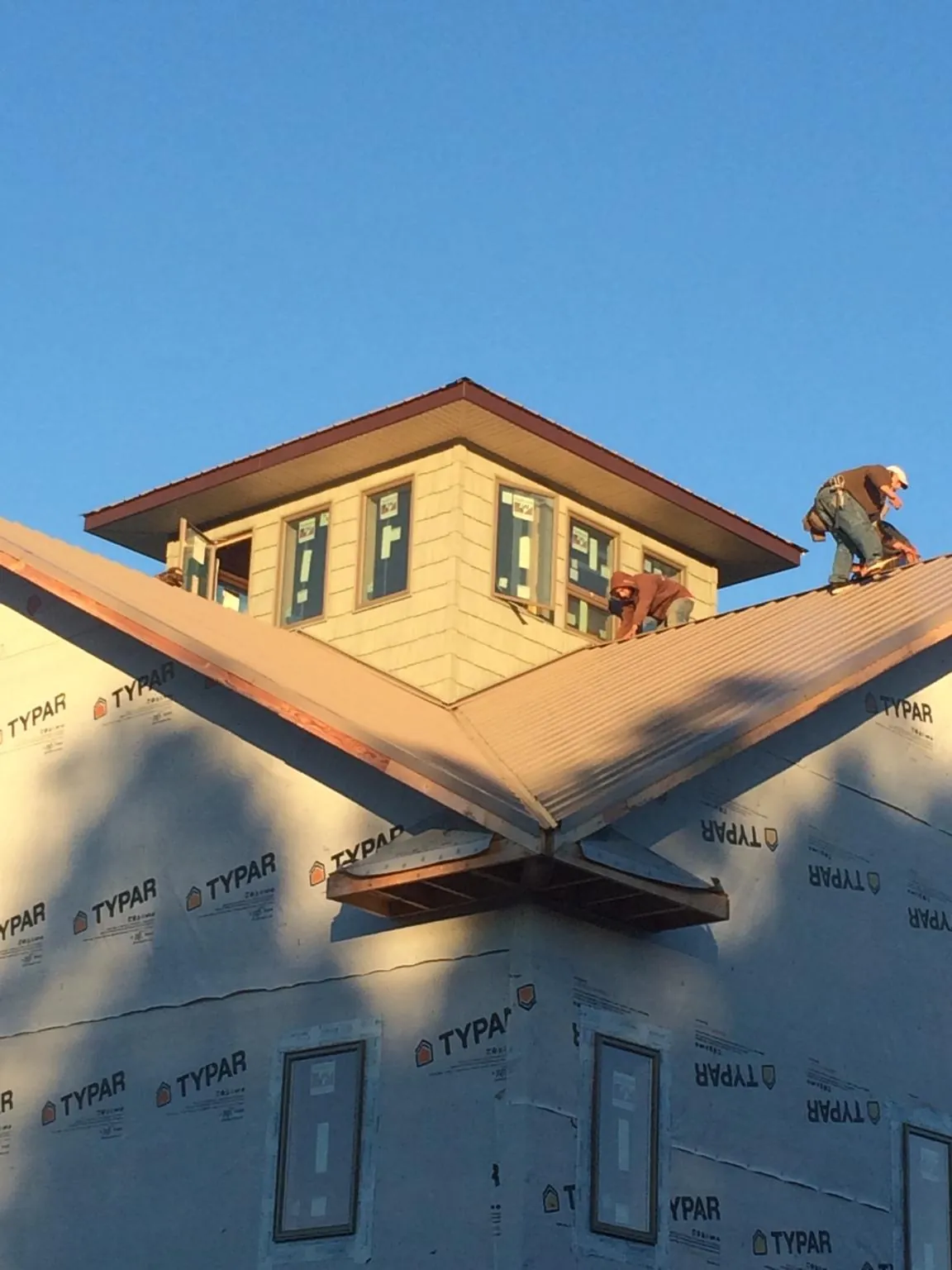 Roofers working around a rooftop cupola on a new metal roof at sunset — Roof Waterproofing in Lurgan by Roofing Brothers